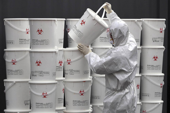 Nhân viên xếp các thùng chứa chất thải y tế từ bệnh nhân tại một trung tâm ở Daegu, Hàn Quốc, hôm 24/2. Ảnh: AP.