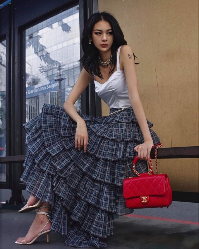 Phí Phương Anh mang đến làn gió mới cho xu hướng street style với áo quai cùng chân váy nhiều tầng. Cô chọn phụ kiện nổi bật là chiếc túi Chanel có quai xách tròn độc đáo, phối cùng sandals cao gót buộc dây.