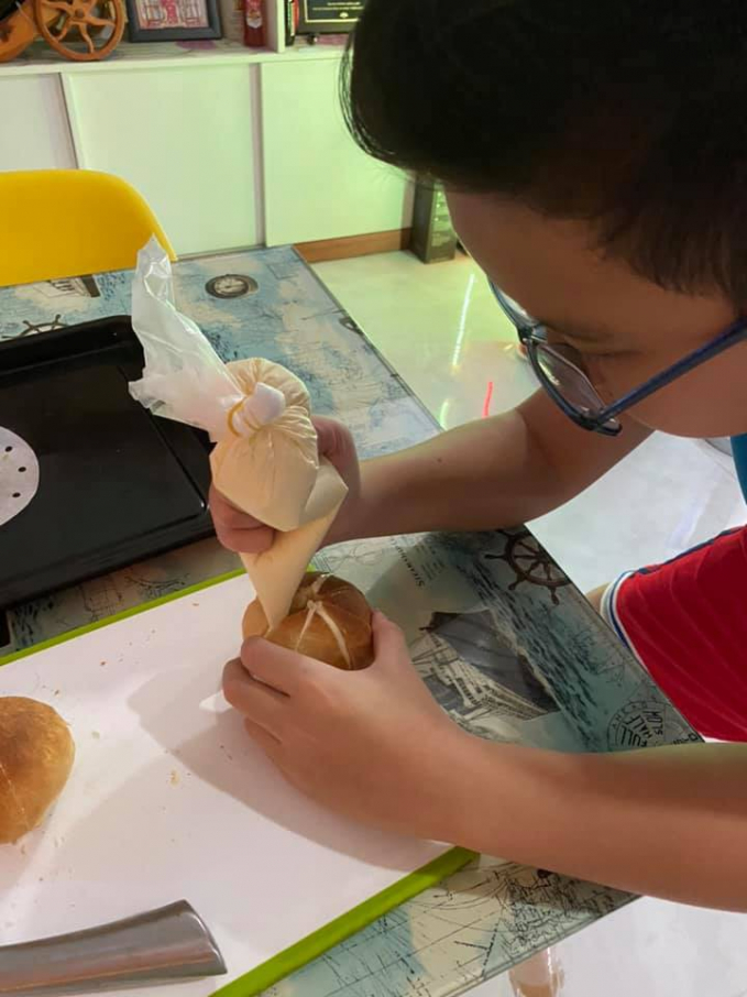 Cậu con trai chị Quyên đang tẩn mẩn làm món bánh mì bơ tỏi.