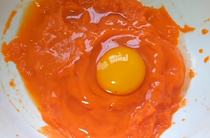 Nghiền nát cà rốt rồi cho 1 quả trứng vào, cùng 3g muối, 3g bột nở đánh đều.