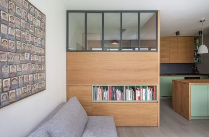 Phòng khách gồm một chiếc ghế sofa lớn cùng một chiếc tủ để đồ đạc cũng đóng vai như tường ngăn giúp chia đôi không gian.