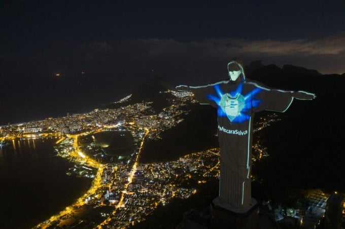 Bức tượng nổi tiếng Chúa Kitô Cứu Thế tại Rio de Janeiro, Brazil được thắp sáng với hình ảnh đeo khẩu trang và dòng chữ bằng tiếng Bồ Đào Nha