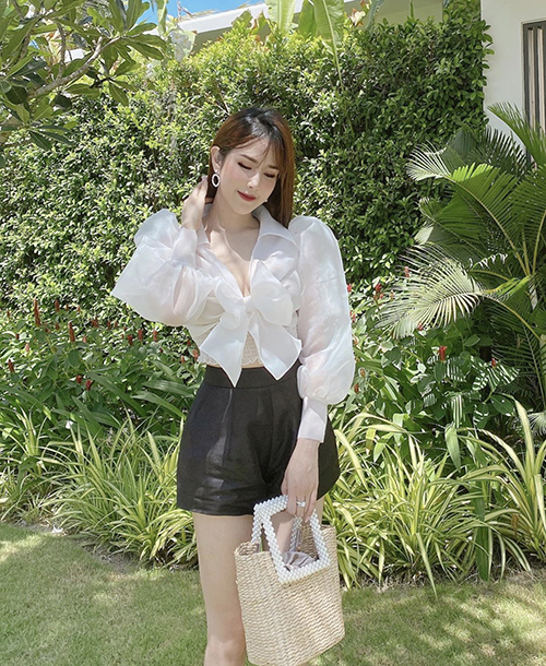 Set đồ đậm chất mùa hè của Diệp Lâm Anh với sơ mi vai bồng, quần short vải linen đen và túi cói thân thiện môi trường.