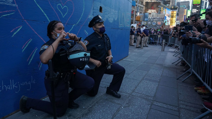 Hai cảnh sát New York quỳ gối trước đám đông người biểu tình ở Times Square hôm 31/5. Ảnh: AFP.