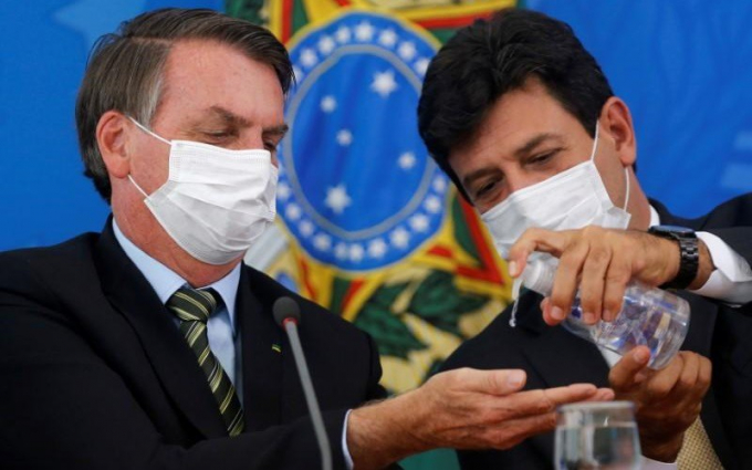 Lãnh đạo Brazil đeo khẩu trang và dùng nước rửa tay khô để phòng Covid-19. Ảnh: Reuters.