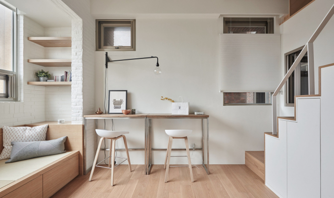 Có hai bàn gỗ đặt dọc theo bức tường trong phòng khách có thể là một bàn dài giúp tiết kiệm phòng và có thể kết hợp theo hướng khác để trở thành bàn ăn. Do đó, không gian trống linh hoạt cho các nhu cầu khác nhau, và làm cho căn hộ nhỏ bớt chật chội.