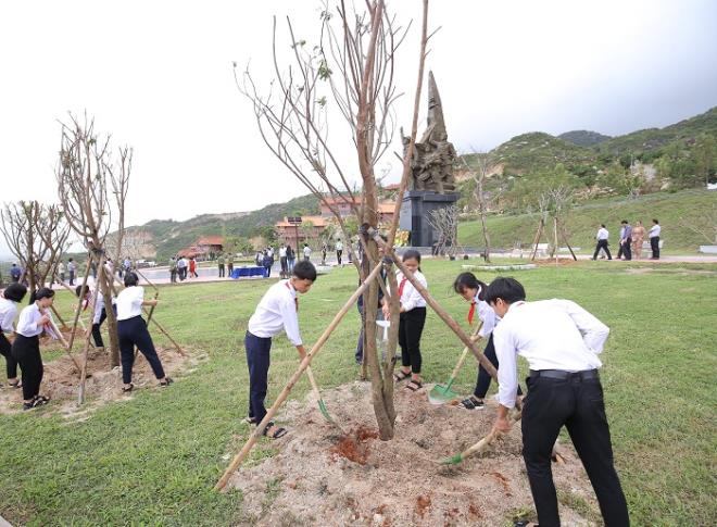 Các em học sinh trồng cây và chụp hình lưu niệm bên những cây xanh vừa trồng trong chương trình “Quỹ 1 triệu cây xanh cho Việt Nam”