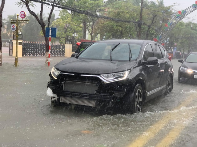 Một chiếc xe ô tô bị sóng nước trên đường đánh hư nhiều bộ phận phía trước xe.
