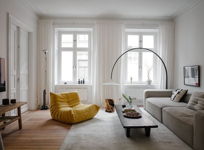 Chiếc ghế sofa thư giãn màu vàng tươi trông vô cùng nổi bật bên trong phòng khách mang phong cách tối giản.