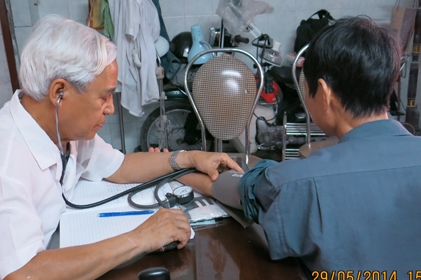  GS.TS Dương Trọng Hiếu đang đo huyết áp và thăm khám cho bệnh nhân.