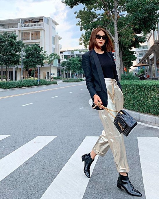 Quần ánh kim là trang phục Thanh Hằng chọn lựa để tô điểm cho set đồ toàn tông đen gồm áo blazer, áo thun, túi Yves Saint Laurent và bốt cổ thấp.
