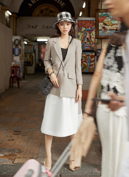  Jolie Nguyễn theo phong cách tối giản khi chọn áo blazer xám ghi để mix cùng áo thun đen và chân váy midi trắng. 