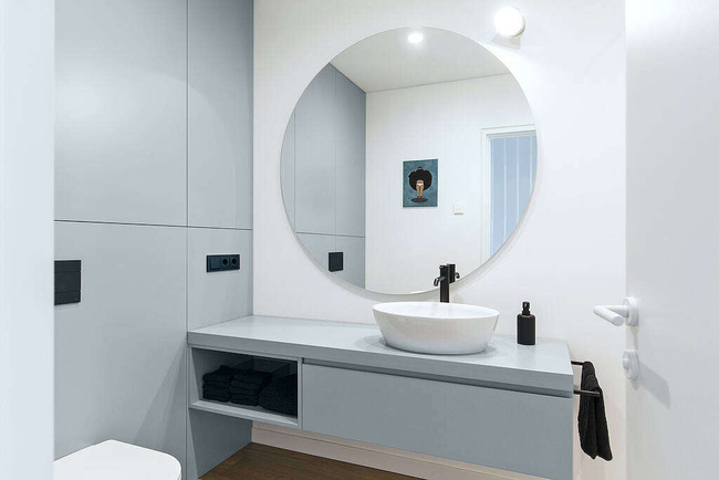  Khu vực phòng tắm sạch gọn nhờ đồ dùng lưu trữ trong kệ tủ ẩn dưới bồn rửa. Một chiếc gương tròn tạo điểm nhấn đặc biệt trong phòng tắm này.