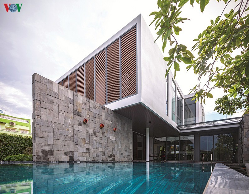  Phong cách kiến trúc hiện đại được thể hiện qua những đường nét, mảng khối mạnh mẽ và ấn tượng. Mặt tiền được thiết kế với một hệ lam chắn nắng và để thêm phần kín đáo. Ở tầng 1 kế bên lối vào có một bể bơi.