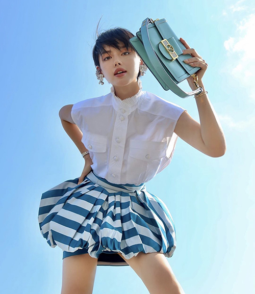  Khánh Linh chọn áo sát nách tông trắng nhẹ nhàng phối cùng chân váy kẻ sọc để thay đổi phong cách mùa hè.