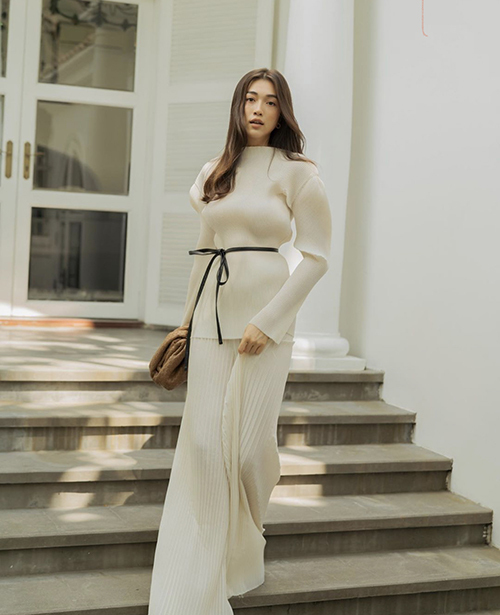 Lệ Hằng thanh nhã với set đồ thiết kế trên vải xếp ly tông màu trắng ngà. Khi mặc bộ cảnh tôn nét mảnh mai, á hậu chọn thêm dây lưng mảnh dẻ, túi da đan để mix đồ.