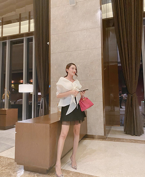 Áo blouse cách điệu, chân váy xếp ly dáng ngắn được Lê Hà chọn lựa để mix-match cùng nhau. Túi Hermes hồng được người đẹp sử dụng để set đồ thêm sang chảnh.