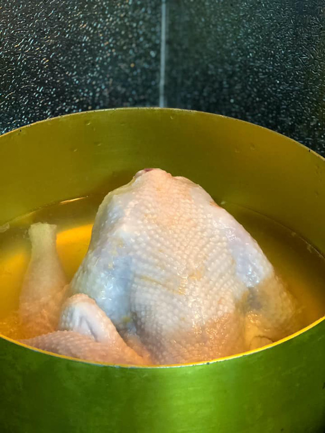  Gà sơ chế sạch, cho vào nồi rồi dội nước sôi khắp thân gà.