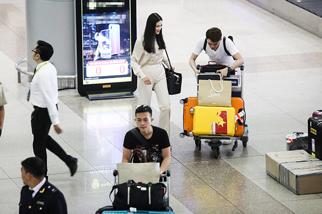 Phương Khánh rạng rỡ tai sân bay. Anh trai của cô (đi phía trước) phụ giúp em gái di chuyển hành lý.