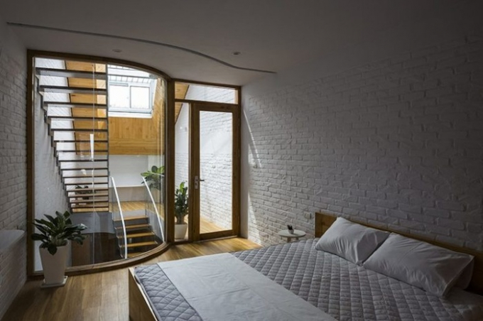 Phòng ngủ được thiết kế đơn giản với giường lớn, cây xanh và bàn nhỏ.