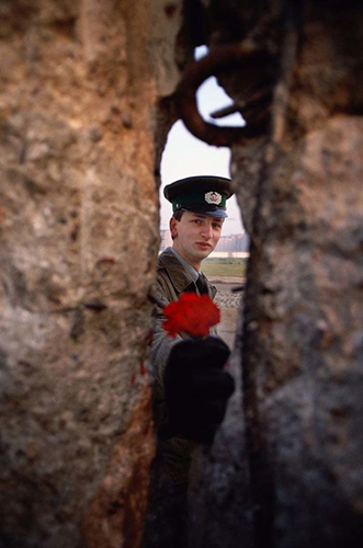 Người lính Đông Đức đưa một bông hoa qua khe hở của Bức tường Berlin năm 1989.