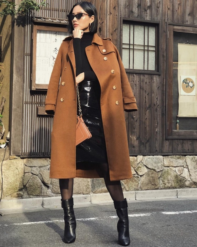Khánh Linh lựa chọn áo len cổ lọ phối chân váy và boots da tiệp màu đen, thêm áo khoác dáng dài tông nâu trầm.