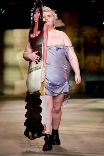 Đây cũng là một trong những thiết kế kỳ quái khác tại tuần lễ thời trang London thu đông 2018. Người mẫu này xuất hiện với bộ cánh rách rưới mang theo tấm bảng in hình siêu mẫu Naomi Campbell.