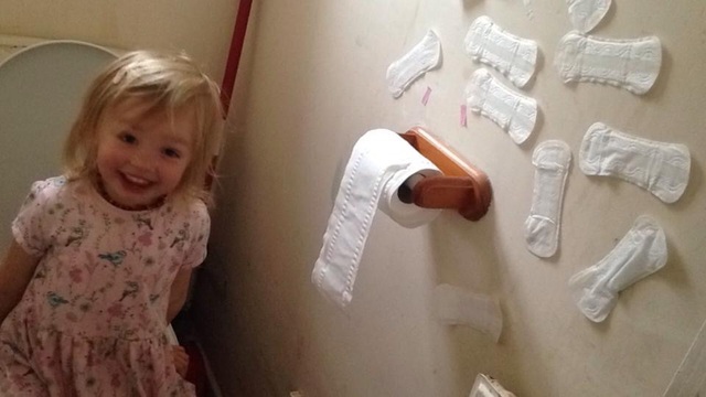  Iris, 3 tuổi, ngồi trong nhà vệ sinh hát váng bài Row Your Boat trong khi bận rộn dán đầy băng vệ sinh hằng ngày của mẹ lên tường. Bức ảnh chụp cho thấy bé cười rất tươi, dường như rất tự hào về công việc đang làm.