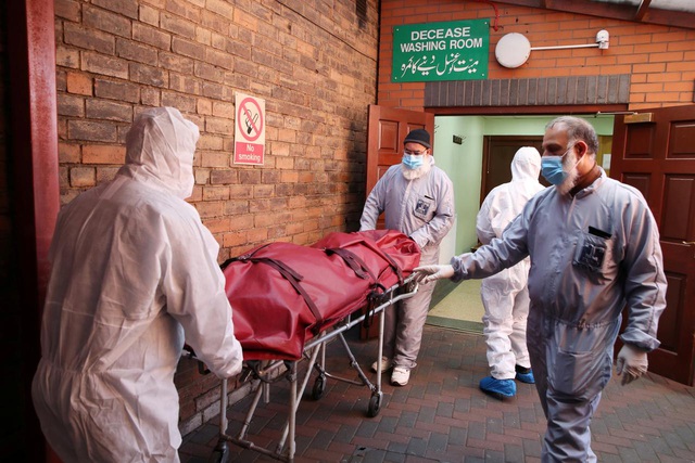  Các nhân viên y tế mặc đồ bảo hộ chuyển thi thể tới nhà xác tạm thời ở Anh. (Ảnh: Reuters)