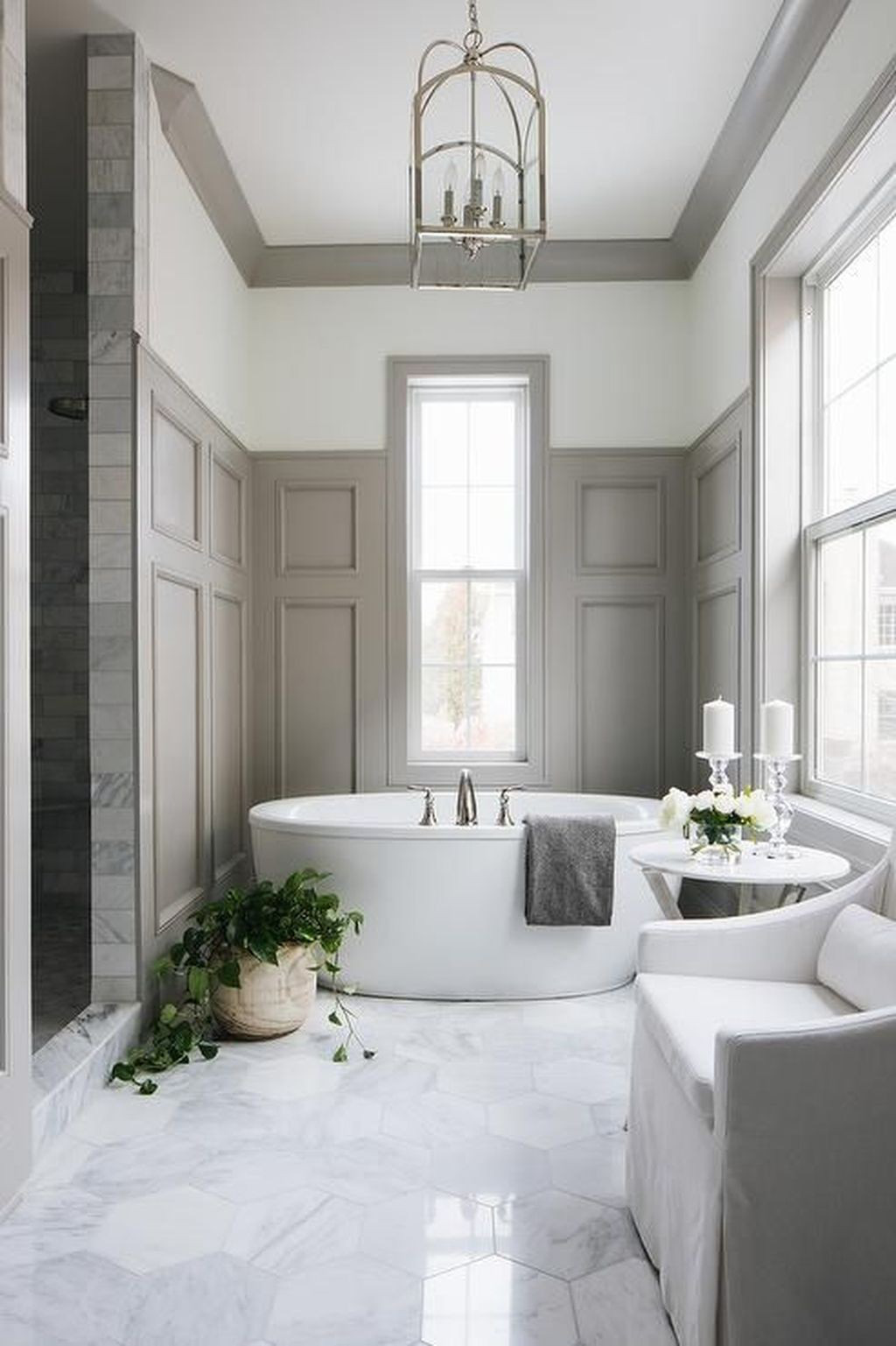  Một phòng tắm thanh lịch tuyệt đẹp được thực hiện với các tấm ốp màu xám nhạt, gạch lục giác bằng chất liệu đá cẩm thạch, đồ nội thất màu trắng và bồn tắm hình bầu dục hiện đại.