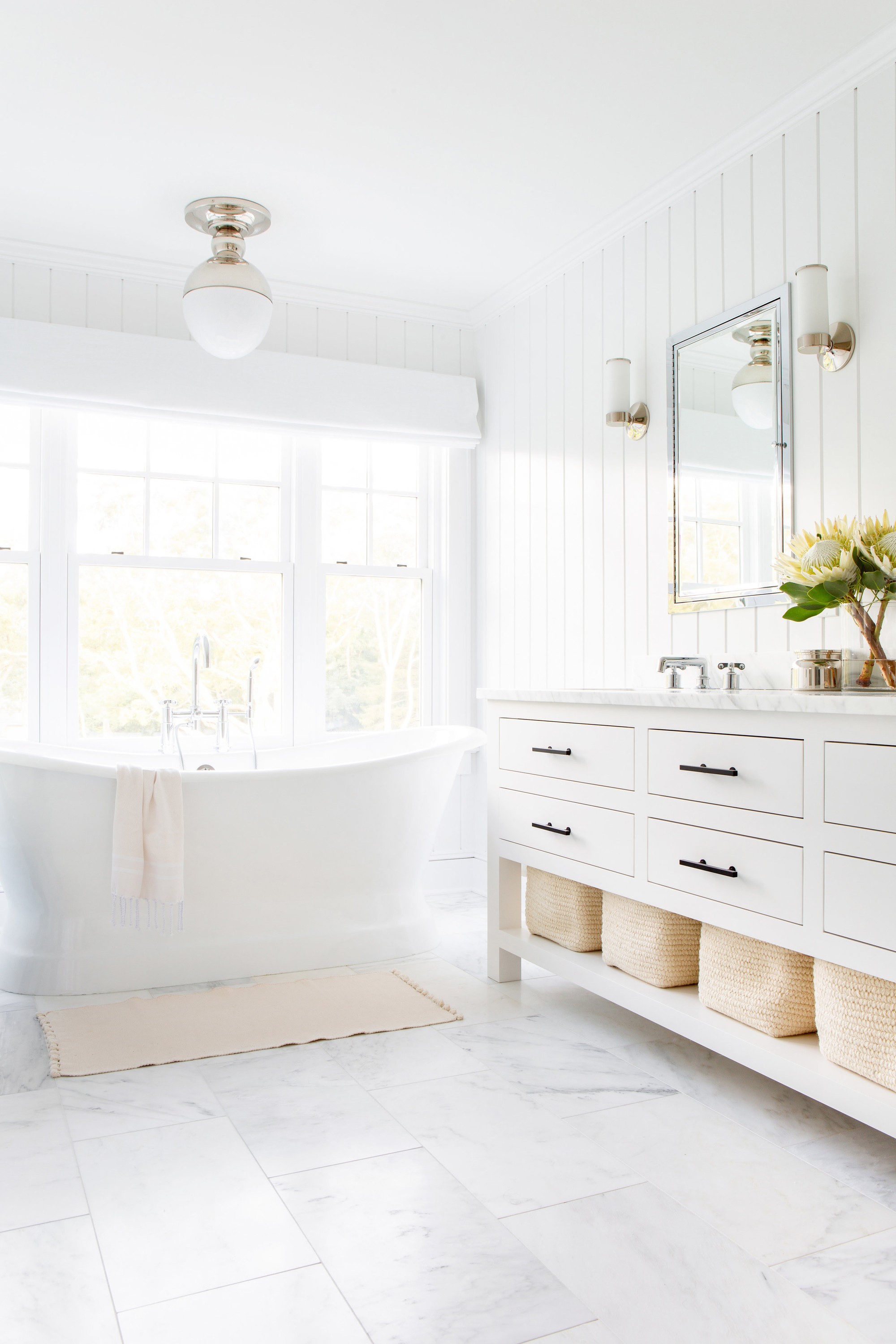  Phòng tắm trắng ngập đầy ánh sáng với bàn trang điểm màu trắng truyền thống, bồn tắm cổ điển và đèn treo cộng với đá cẩm thạch.