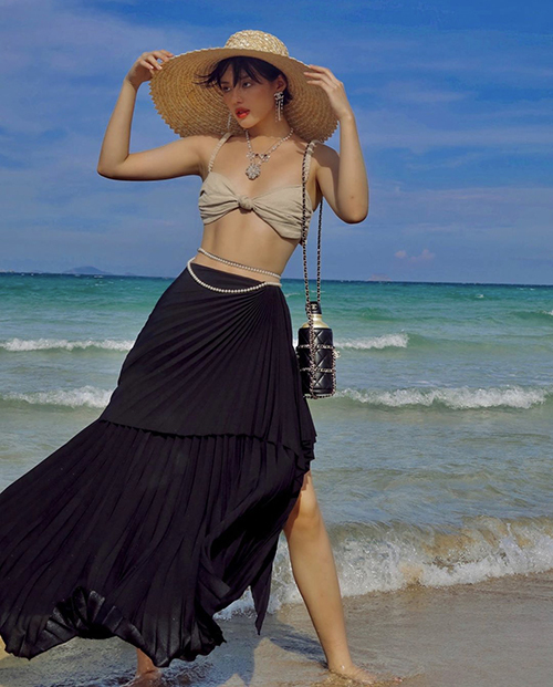  Khi đi du lịch biển, Khánh Linh mix-match trang phục còn kỳ công hơn cả những set đồ street style. Phụ kiện túi đựng nước sang chảnh của Chanel được fashionista phối hợp ăn ý với hoa tai, vòng cổ, vòng eo.