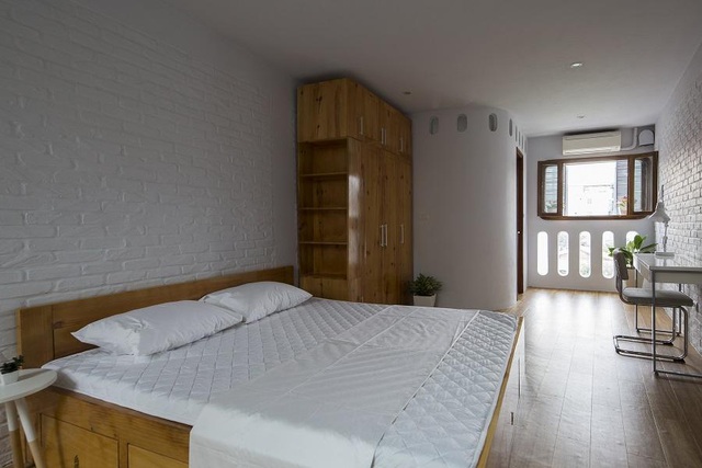  Tường, chăn nệm, bàn ghế đều sử dụng tông trắng khiến nhà có cảm giác rộng rãi hơn so với diện tích thật. Góc phòng ngủ có các ô cửa sổ được uốn cong mềm mại.