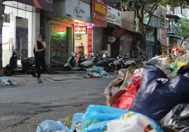  Một người dân dùng tay bịt mũi khi đi ngang qua đống rác trên phố Yên Phụ.