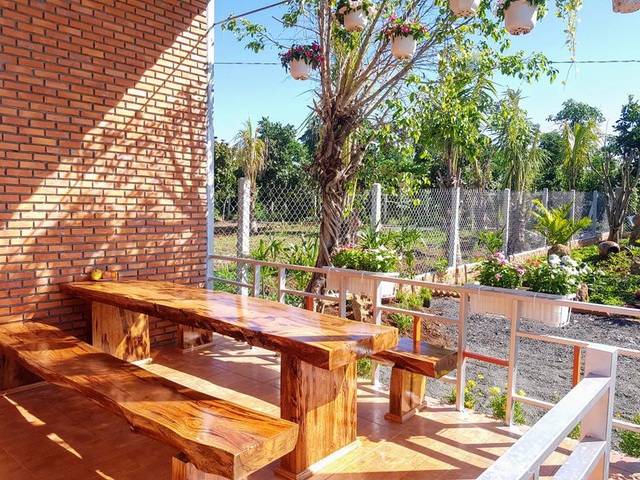  Phía trước nhà là khu vực sảnh có mái hiên với bộ bàn ghế gỗ. Gia chủ có thể ngồi đây ngắm toàn cảnh khu vườn, nhâm nhi chén trà.