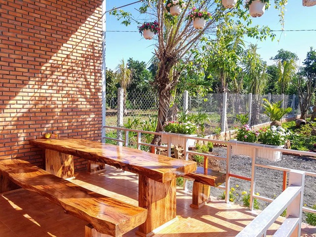 Phía trước nhà là khu vực sảnh có mái hiên với bộ bàn ghế gỗ. Gia chủ có thể ngồi đây ngắm toàn cảnh khu vườn, nhâm nhi chén trà.
