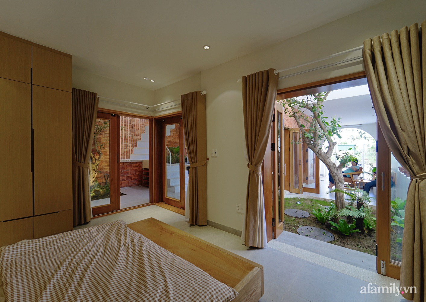  Khu vực phòng ngủ được bố trí ngăn cách với khu vực chính bằng cửa kính khung gỗ và rèm để tạo sự riêng tư cần thiết.