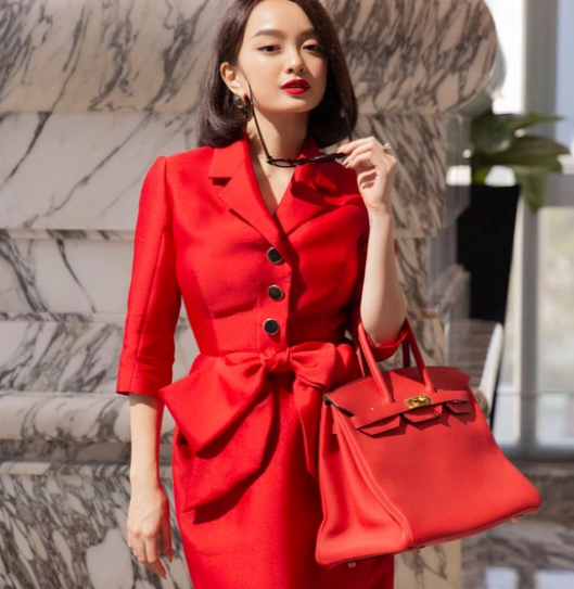  Cô diện thiết kế đỏ, cổ giả vest, chân váy bút chì với chiếc nơ ở eo làm điểm nhấn, tạo sự khác biệt so với những thiết kế công sở thường thấy. 