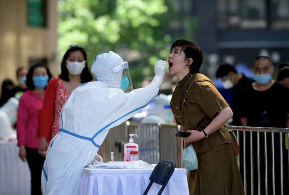  Nhân viên y tế lấy mẫu xét nghiệm COVID-19 cho một phụ nữ ở Bắc Kinh, Trung Quốc vào ngày 15-5 - Ảnh: AFP