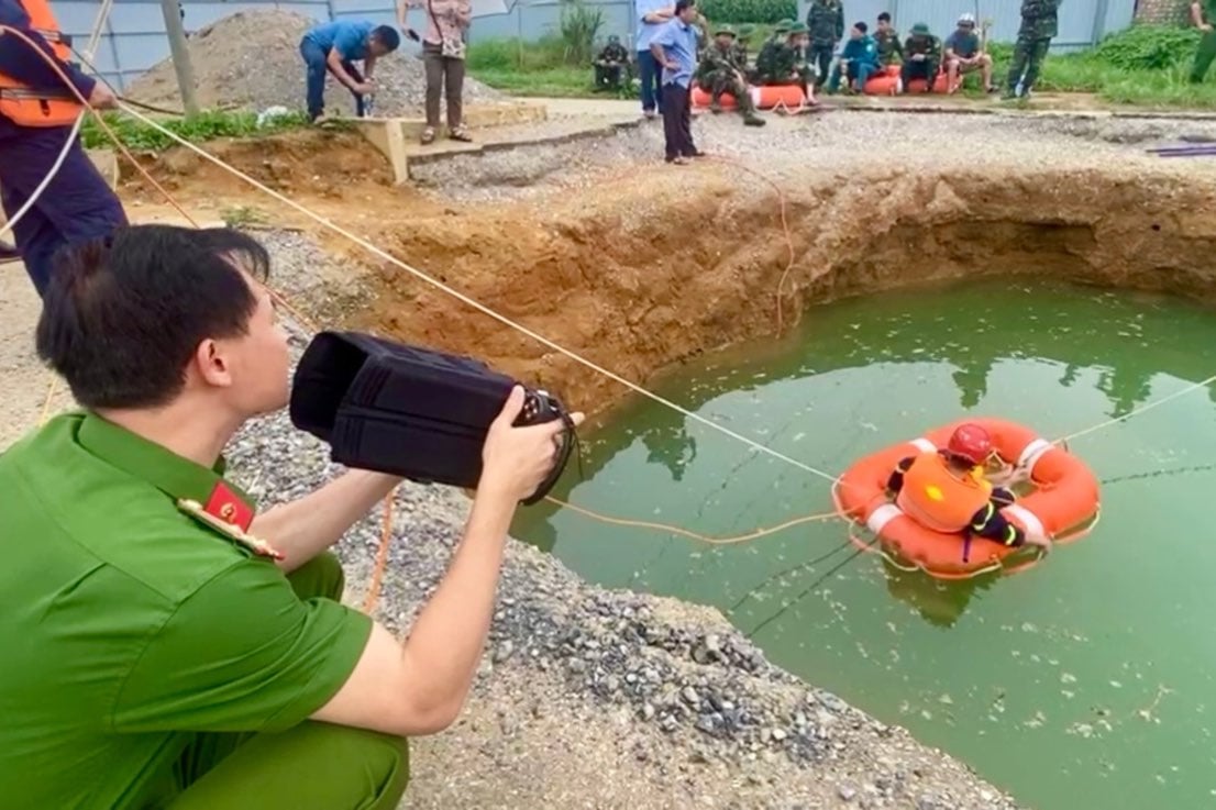 Dùng camera chuyên dụng để dò tìm nhưng gặp nhiều khó khăn do nước trong hố đục ngầu. Ảnh: Báo Lao Động.