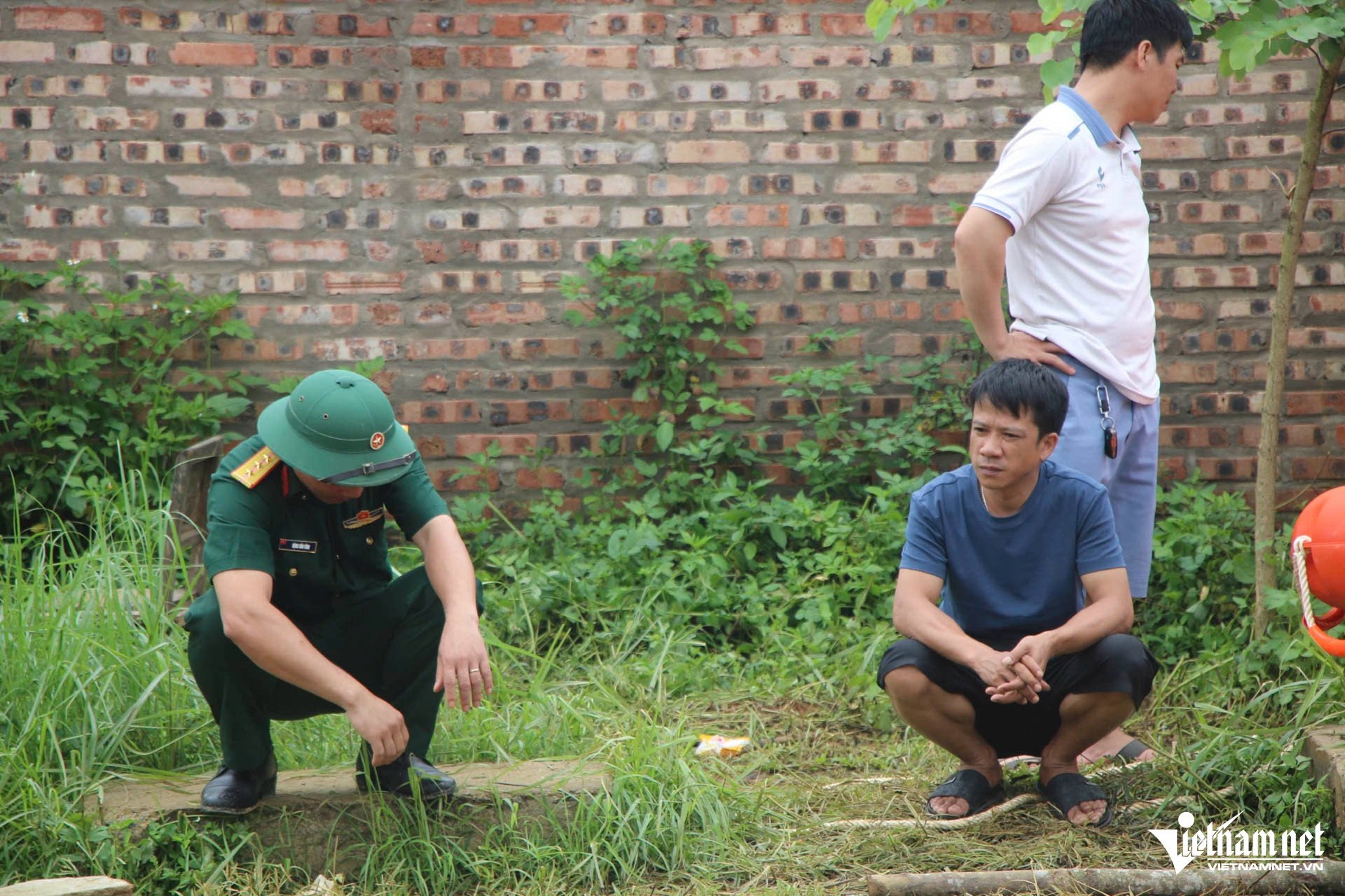 Anh Nguyễn Duy Tiến ngồi dõi theo lực lượng chức năng tìm kiếm em trai - Ảnh: VietNamNet