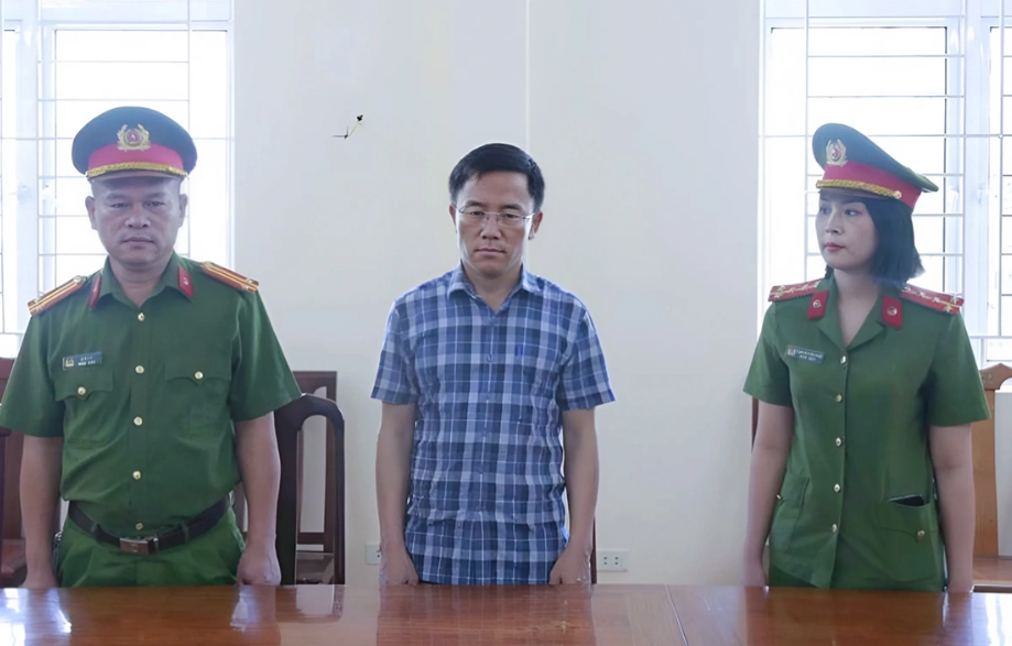 Ông Nguyễn Văn Hưng (đứng giữa), nghe cảnh sát đọc lệnh bắt. Ảnh: Công an cung cấp