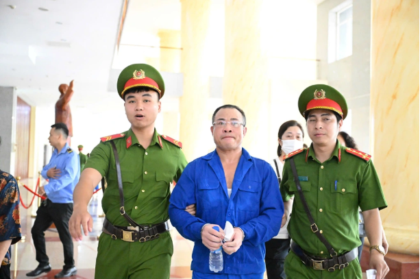 Bị cáo Nghiêm Quang Minh được dẫn giải đến phiên xét xử - Ảnh: Báo Dân trí