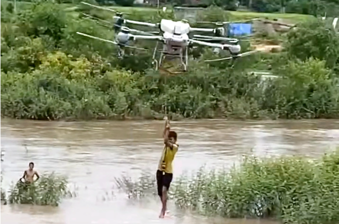 Người dân dùng máy bay không người lái cứu 2 cháu nhỏ mắc kẹt dòng lũ - Ảnh: Báo Dân trí