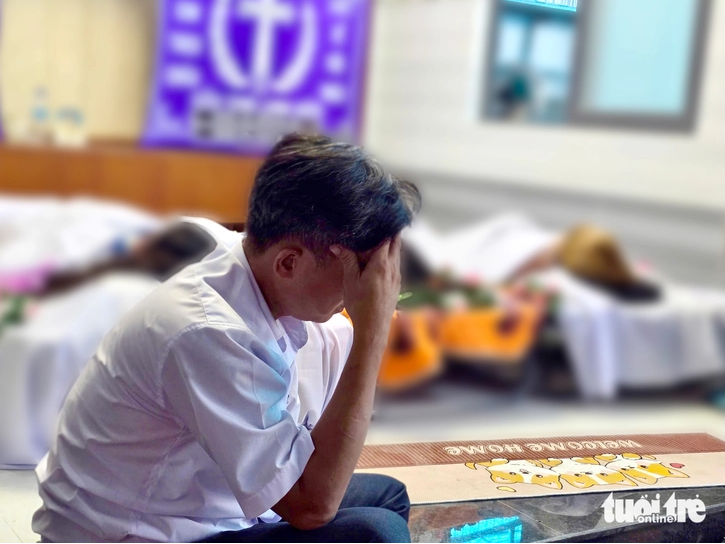Anh Phong ngồi gục đầu bên thi thể mẹ và hai con gái - Ảnh: Báo Tuổi Trẻ