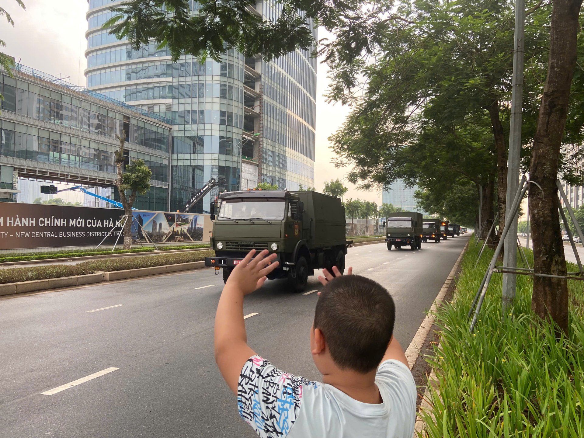 Bạn nhỏ vẫy tay chào khi đoàn xe khí tài đi qua
