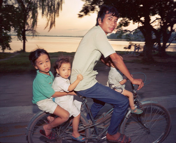 Ông bố chở ba đứa con bằng xe đạp trên đường Thanh Niên, 1987.