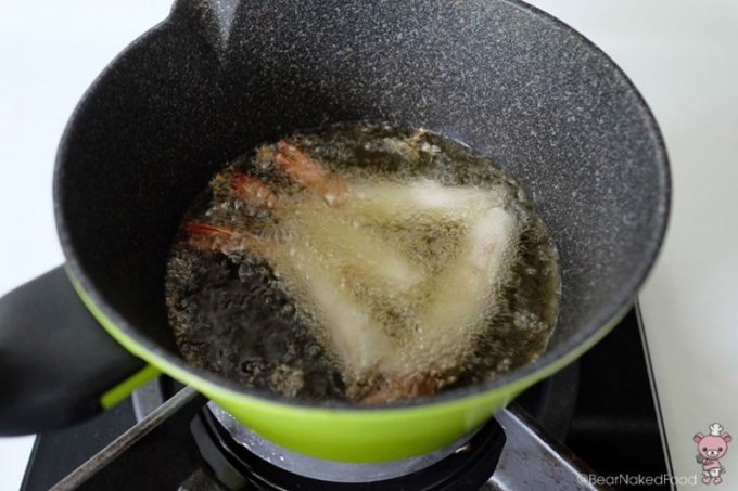 Cẩn thận thêm vào từng cuộn tôm vào chảo và chiên ngập dầu trong khoảng 2 phút, cho đến khi vỏ ngoài chuyển sang màu nâu vàng.